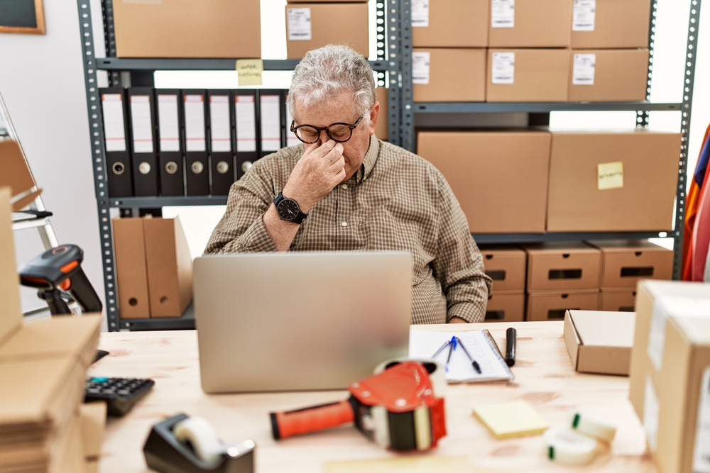 Quais erros as empresas mais cometem ao fazer entregas de última milha - man working at small business ecommerce with laptop tired rubbing nose and eyes feeling fatigue and headache. stress and frustration concept - borzo